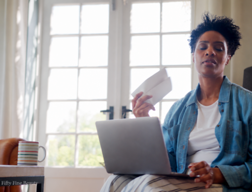 Woman cooling herself with a paper fan during hot flashes in perimenopause.