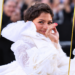 Three-photo editorial banner of Zendaya’s textured pixie hairstyle and white ruffled Louis Vuitton fashion show look, with a waving photo in the center