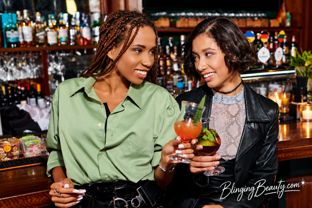Two Black women enjoying cocktails together at a bar after work