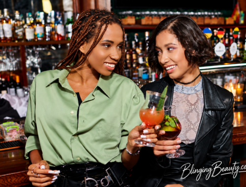Two Black women enjoying cocktails together at a bar after work